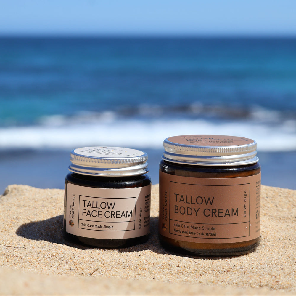 Three jars of Tallow Face and Body Cream on a reflective surface with a blue background